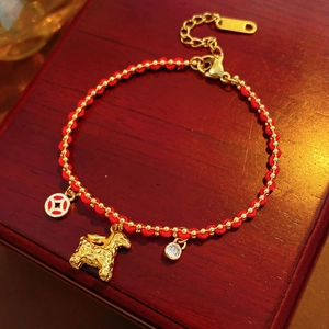 Detailed macro view of 18K gold-plated red rope bracelet with horse and coin charms