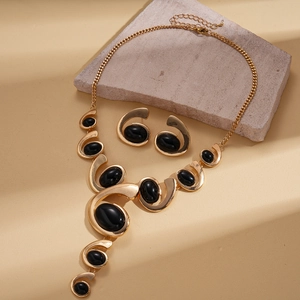 Detailed close-up of gold geometric necklace and earrings with black oval stones