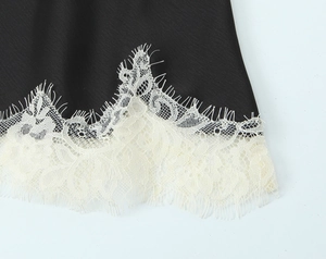 Detailed macro view of black satin fabric with ivory eyelash lace trim on the hem