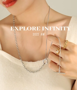 Detail of silver OT clasp sweater chain and gold rings worn by model on beige knitwear