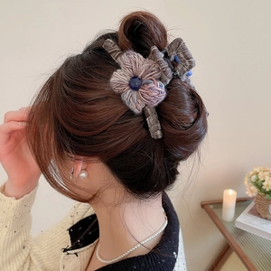 Detailed view of an autumn knitted flower hair claw clip on a stylish bun hairstyle