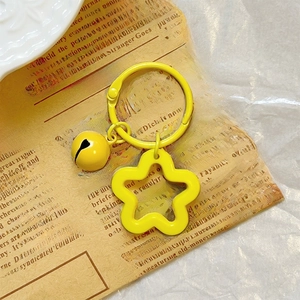 Close-up of a yellow acrylic star keychain with a round metal bell on a vintage background