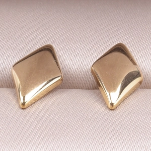 Detailed close-up of gold geometric diamond earrings on elegant pink satin background
