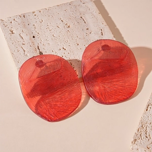 Detail of red translucent resin earrings with unique textured finish on stone