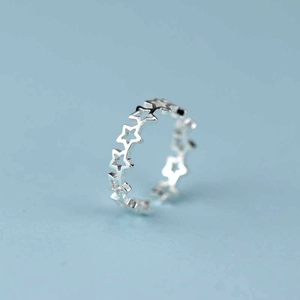 Anello aperto in argento con stelle traforate su sfondo azzurro chiaro
