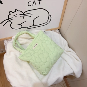 Detail of light green floral quilted texture and simple wish label on tote bag