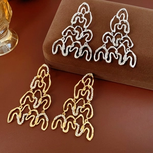 Detail of layered wavy geometric earrings with sparkling rhinestones in gold and silver