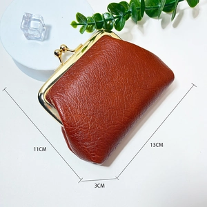 Mini vintage brown pebble leather coin purse with golden metal clasp on white display tray