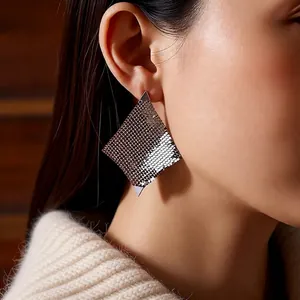 Élégantes boucles d'oreilles losanges en maille métallique argentée portées par un modèle