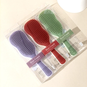 Three colorful hair detangling brushes in purple, red, and green with gift box packaging