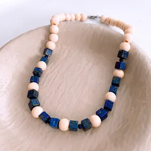 Vintage lapis lazuli and wooden bead necklace on a stylish ceramic jewelry tray