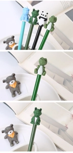 Close-up of 3D silicone animal toppers on cartoon pens featuring dinosaur and frog designs