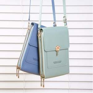 Detail view of the mint green and light blue crossbody bags with dual zippers and floral charm