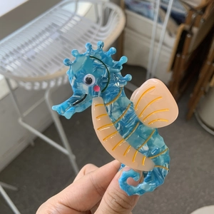 Cute seahorse hair claw clip in blue marble acetate material shown from a side view