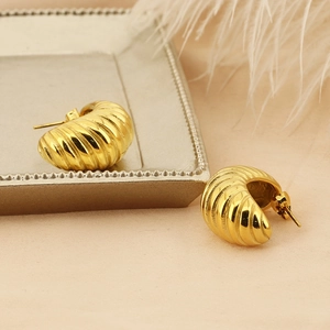 Detail of gold spiral hoop earrings with croissant texture on a vintage display plate
