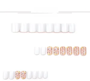 Detail of white flower press-on nails with gold foil accents on a square short shape