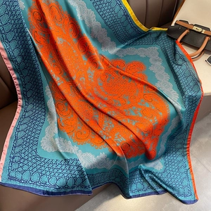 Carré de soie classique bleu et orange au motif cachemire sur canapé en cuir