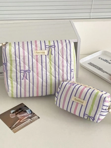 Detail of two purple striped quilted cosmetic bags with bow patterns and brand labels