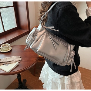 Détail du sac à bandoulière argenté métallisé avec zips multiples et longs glands