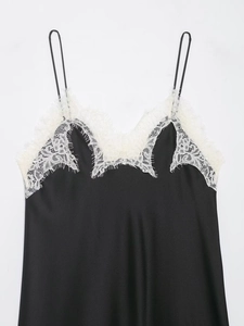 Détail d'un caraco en satin noir avec bordure en dentelle blanche raffinée au décolleté