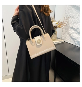 Close-up of crocodile-embossed leather texture and gold floral clasp on off-white handbag