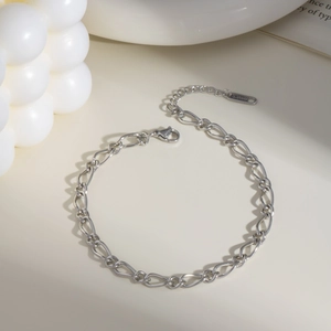 Minimalist silver stainless steel chain anklet with S.STEEL tag on beige surface