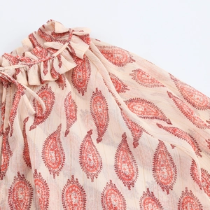 Detail of ruffle neckline and tie-up design on beige paisley chiffon blouse
