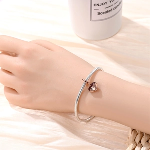 Detail of silver snake chain bracelet with rose gold heart charm engraved with Chocolate