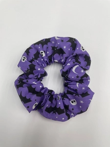 Detail of purple fabric scrunchie with Halloween motifs like bats, ghosts and stars