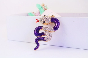 Close-up of purple enamel snake keychain with sparkling rhinestones and golden base