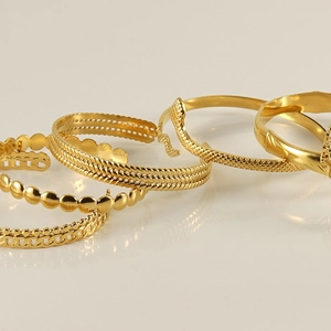Detail of diverse gold-plated stainless steel bangles featuring twist and honeycomb patterns