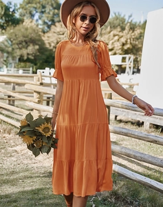 Détail d'une robe d'été orange à volants avec manches courtes dans un cadre champêtre
