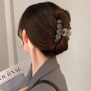 Minimalist smoky grey acrylic hair claw clip with ball design shown on a stylish updo