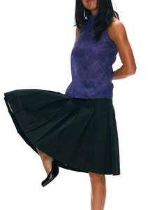 Detail of a purple plaid sleeveless top paired with a black pleated midi skirt on a model