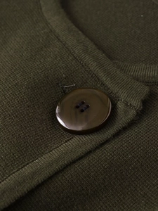 Gros plan du bouton en résine brune et de la maille fine sur ce cardigan vert olive