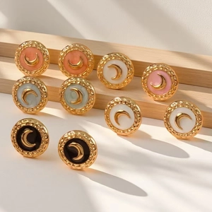 Macro detail of retro moon enamel earrings with golden hammered texture on wood stand