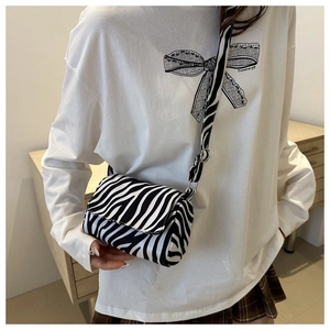 Detail of zebra pattern crossbody bag with wide adjustable strap on a female model