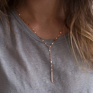 Detail of rose gold Y-shaped necklace with vertical bar pendant on sequin chain