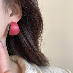 Close-up of a matte dark red C-shaped acrylic earring on model with soft beige knitwear