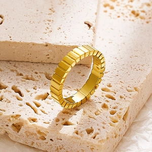 Detailaufnahme eines goldenen Titanrings mit minimalistischen rechteckigen Gittermustern