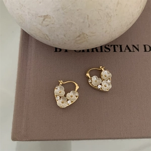 Close-up of 18k gold plated heart earrings with white flowers and zircon on a book