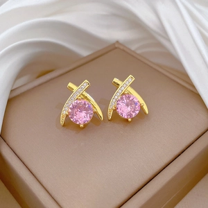 Macro detail of gold teardrop earrings with pink main stone and white cubic zirconia