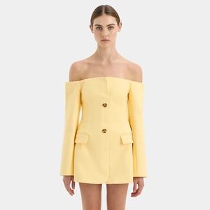 Detail view of double-breasted buttons and flap pockets on light yellow off-shoulder dress