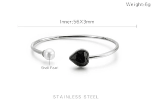 Detail of stainless steel bangle with black heart gemstone and white pearl ornament