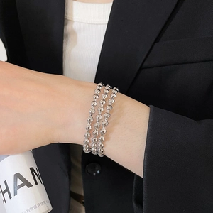 Close-up of three-layer silver beaded bracelet on wrist with elegant black blazer style
