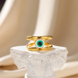 Detail of gold evil eye ring with hammered texture on a white decorative pedestal