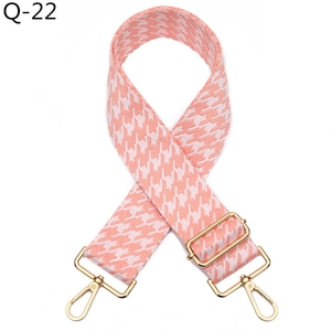 Macro shot of wide pink houndstooth bag strap with adjustable gold alloy swivel hooks