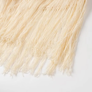 Dettaglio delle morbide frange beige sul set boho di top e gonna lunga in maglia