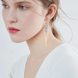 Detailed view of elegant long gold tassel earrings with colorful gradient beads on a model