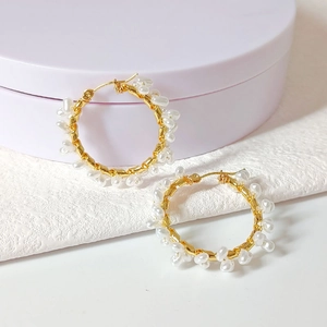 Detailed shot of handmade gold hoop earrings with wrapped white irregular pearls
